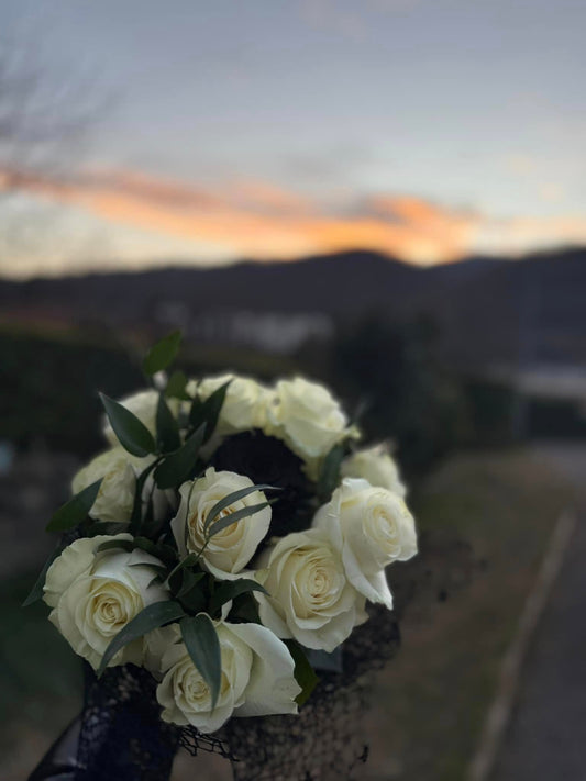 Bouquet sofisticato di rose bianche e nere con rete decorativa nera, realizzato a mano, ideale per eventi speciali e regali raffinati
