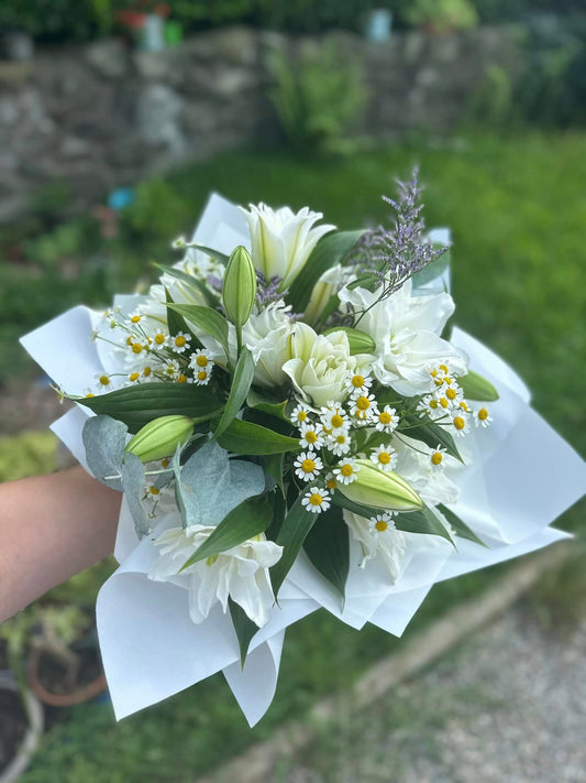 Bouquet grande con gigli a fiore doppio e camomilla, avvolto in incarto elegante, ideale per regali o occasioni speciali.