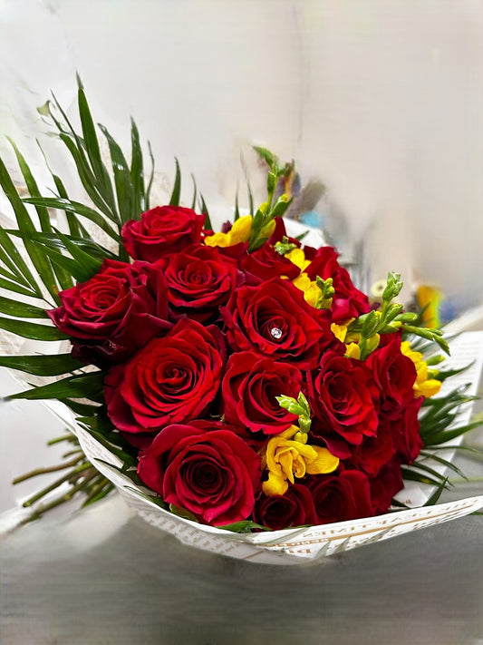 Bouquet grande di rose rosse, arricchito con fresia o fiori di stagione, confezionato con incarto e fiocco elegante.