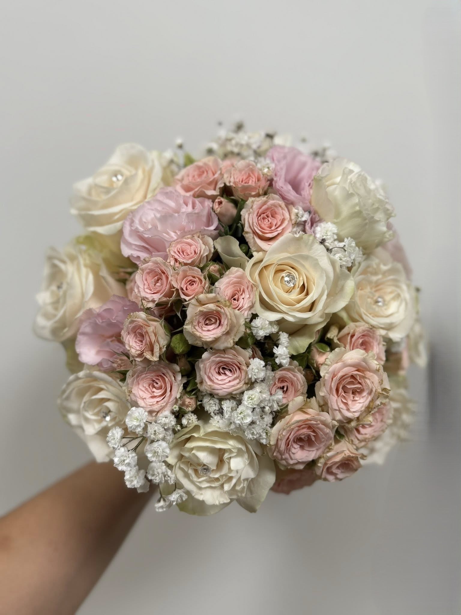 Bouquet compatto di rose e diamanti, colori tenui personalizzabili, rifinito con fiocco elegante, misura media.