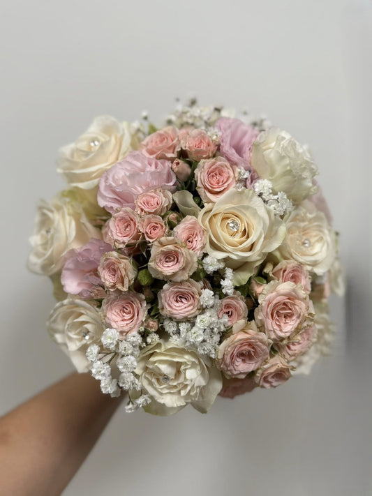 Bouquet compatto di rose e diamanti, colori tenui personalizzabili, rifinito con fiocco elegante, misura media.