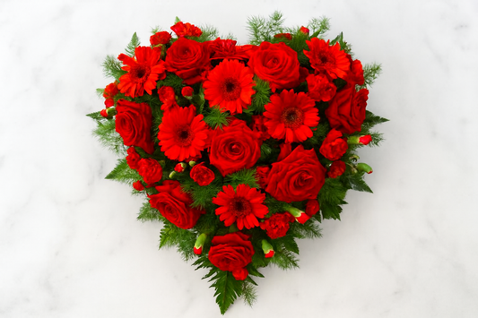 Composizione floreale a cuore con rose rosse e gerbere fresche, personalizzabile nei fiori e nei colori, ideale per anniversari, omaggi e occasioni speciali.
