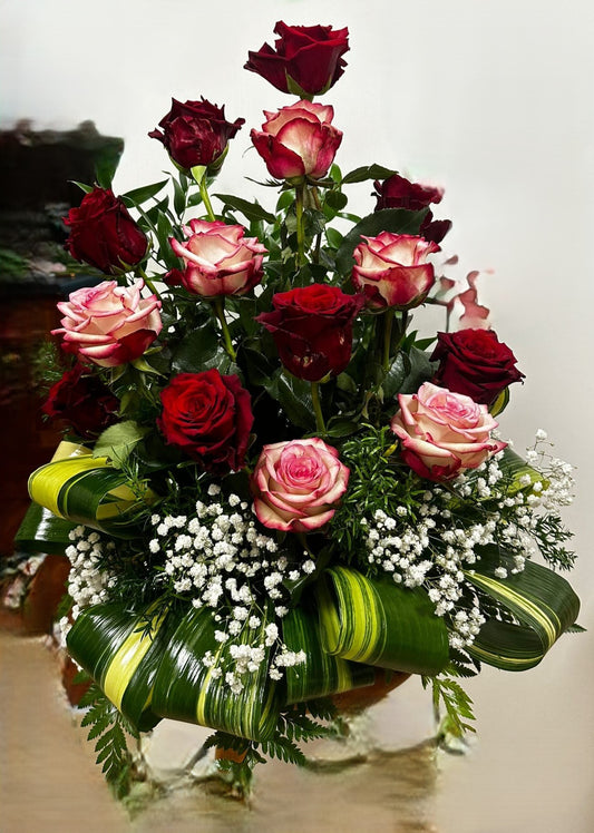 Composizione in ciotola con rose di vari colori e foglie decorative, misura media, elegante per tombe o omaggi commemorativi.
