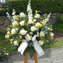 Composizione funebre elegante con fiori freschi di stagione nei toni chiari e delicati, personalizzabile nei fiori, colori e nastro commemorativo, ideale per rendere omaggio con rispetto e affetto.