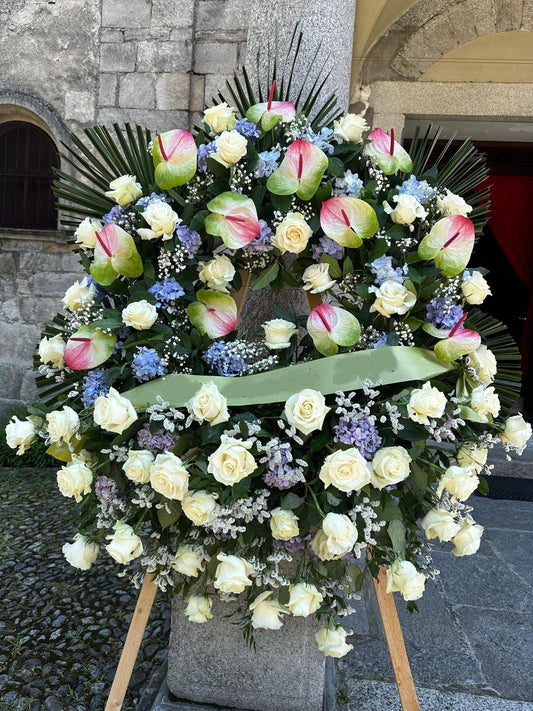 Corona funebre elegante con rose e anthurium freschi, personalizzabile nei colori e fiori, disponibile in misura media (80 cm) e grande (140 cm), con nastro su richiesta.