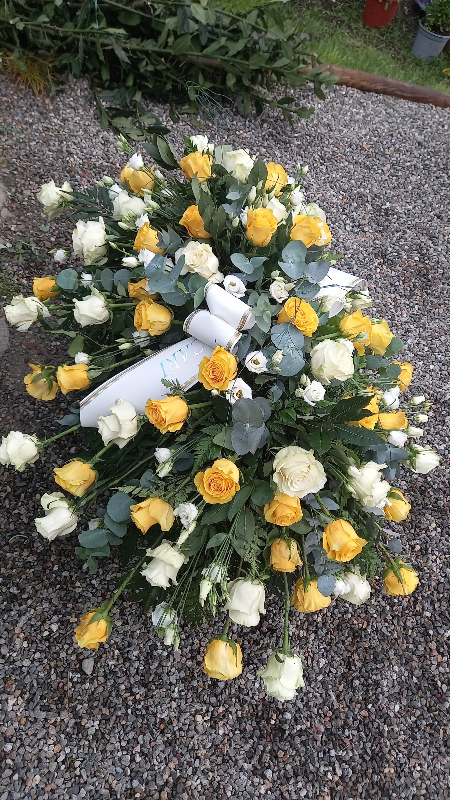 Composizione funebre a cuscino con rose e lisianthus freschi, con nastro personalizzato. Ideale per bara o come omaggio floreale importante.
