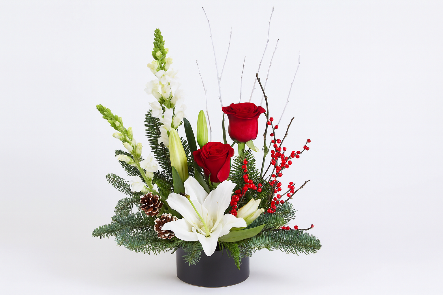 Composizione natalizia in stile ikebana giapponese, con rami di pino, pigne naturali e fiori di stagione. Design minimalista ed elegante, ideale come centrotavola o decorazione d’ambiente.