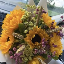 Bouquet rustico con girasoli, spighe e limonium, legato con fiocco di juta naturale. Stile campestre, ideale per matrimoni country o eventi all’aperto.