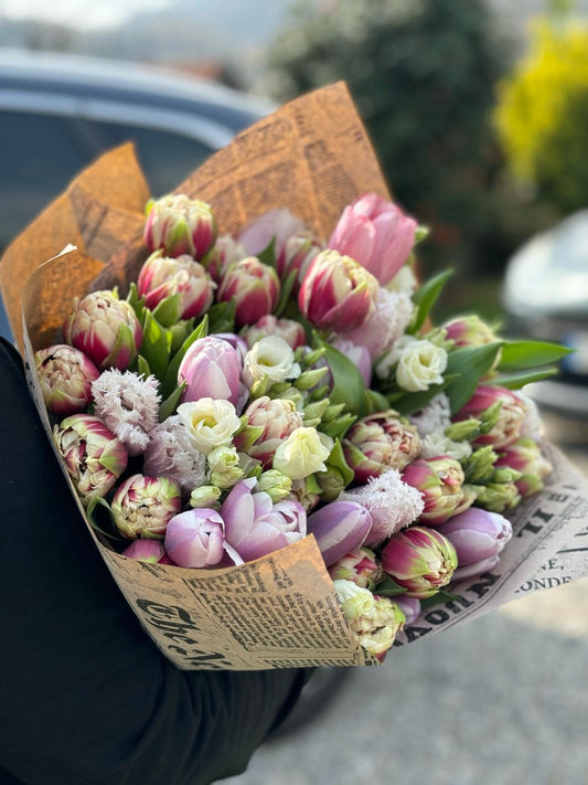 Bouquet elegante con tulipani freschi e fiori di stagione, confezionato con incarto stile giornale per un tocco vintage e originale.