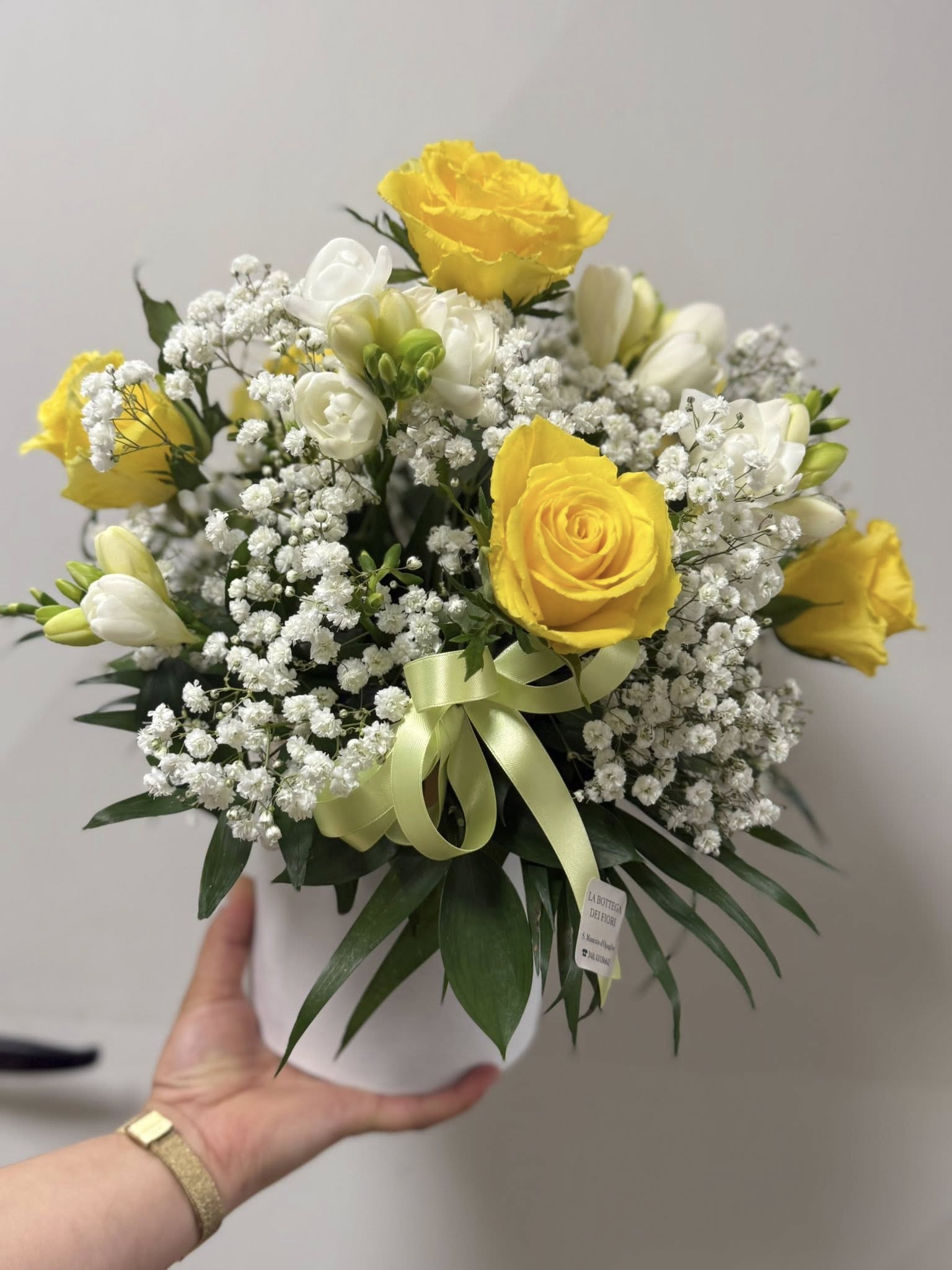 Composizione floreale piccola circa 25x25 cm con rose gialle e bianche, lisianthus e gypsophila. Colori luminosi e delicati, ideale per compleanni, congratulazioni o come decorazione d’ambiente. Scatola riutilizzabile inclusa.