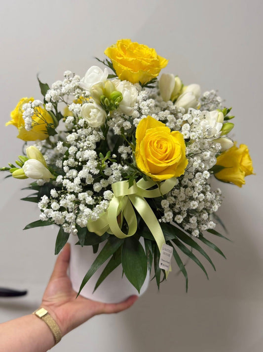Composizione floreale piccola circa 25x25 cm con rose gialle e bianche, lisianthus e gypsophila. Colori luminosi e delicati, ideale per compleanni, congratulazioni o come decorazione d’ambiente. Scatola riutilizzabile inclusa.